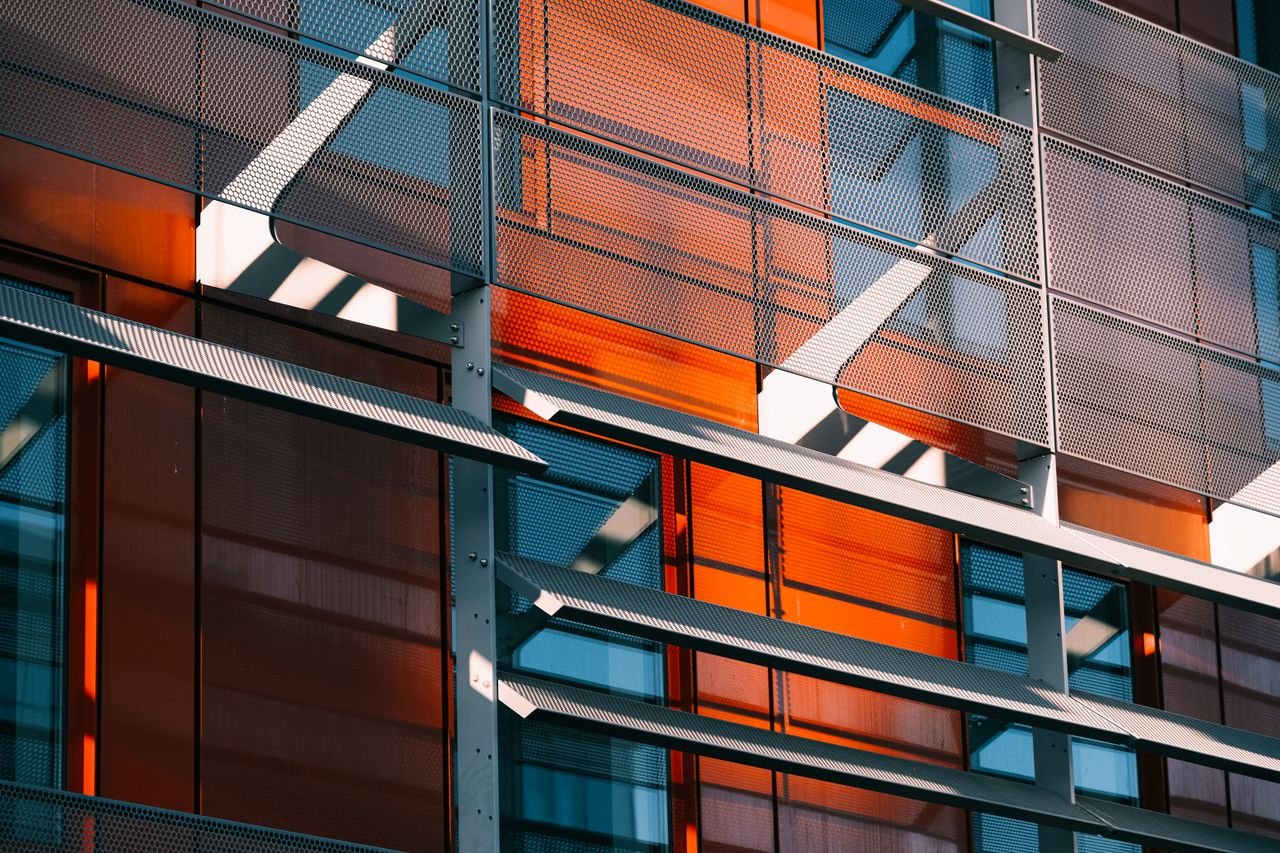 Mastering the First Impression: Your intriguing post title goes here Abstract view of a modern facade featuring metal grids and colorful glass panels, showcasing contemporary architecture design.